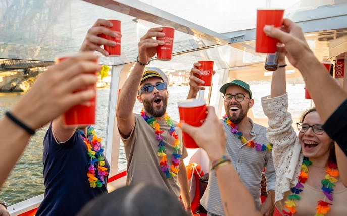 Partygoers with drinks and leis on a Douro River cruise in Porto, Portugal.
