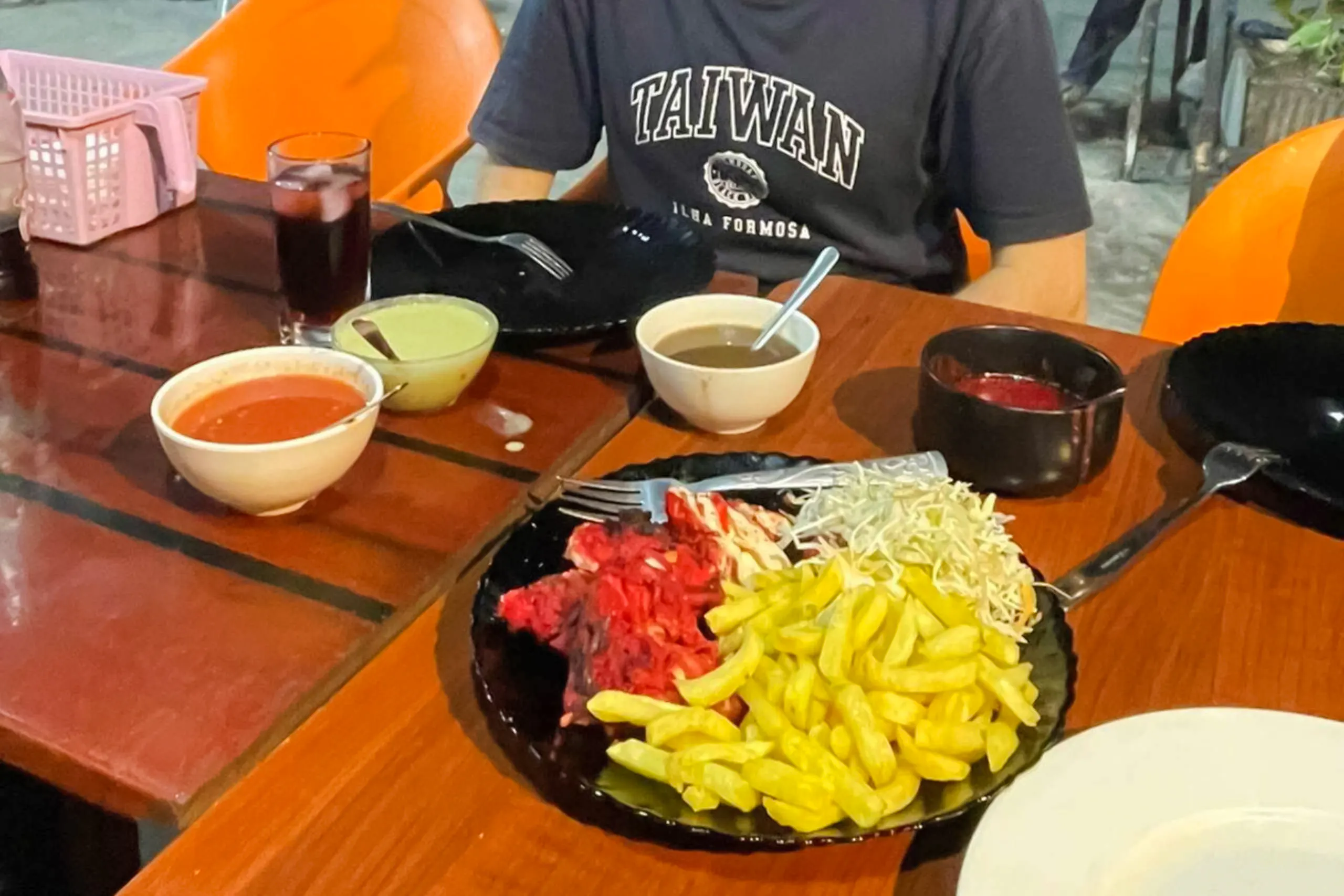 Dining table with local dishes during Dar es Salaam night tour, featuring fries and salads.