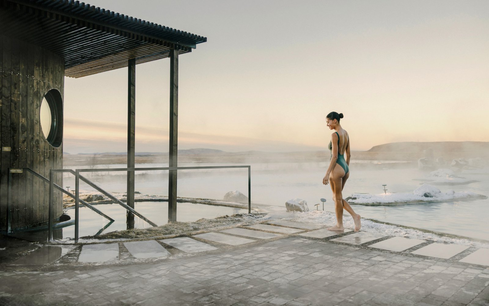 Guest walking by the cold pool in Laugarás Lagoon, Iceland at sunrise.
