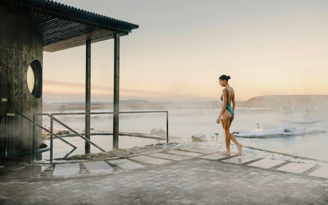 Guest walking by the cold pool in Laugarás Lagoon, Iceland at sunrise.