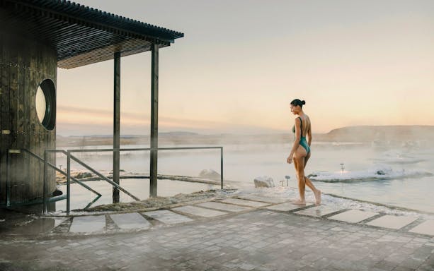 Guest walking by the cold pool in Laugarás Lagoon, Iceland at sunrise.