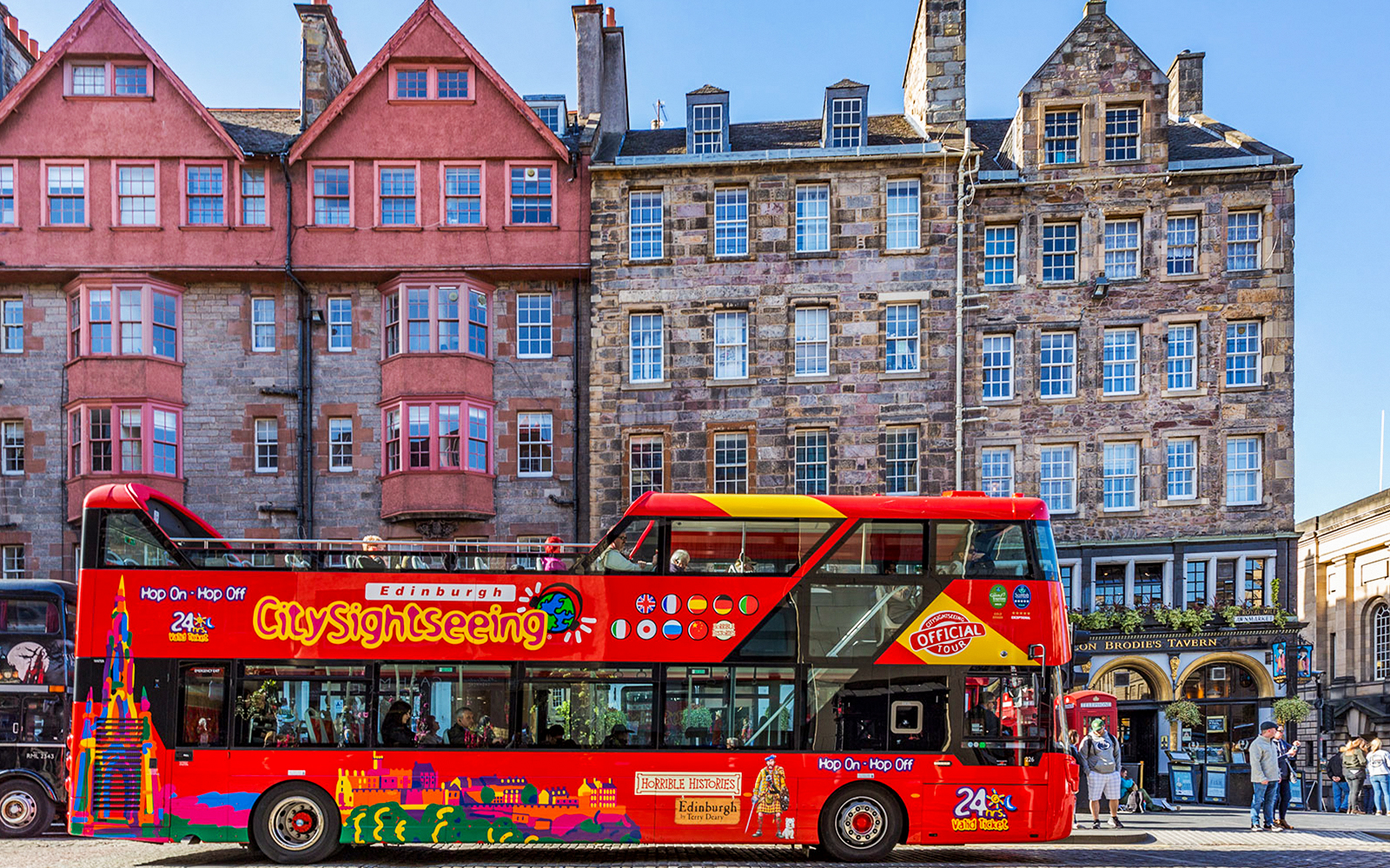 Hop-On Hop-Off bus in front of historic Edinburgh buildings.