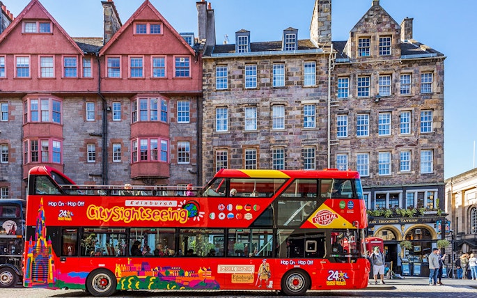Hop-On Hop-Off bus in front of historic Edinburgh buildings.