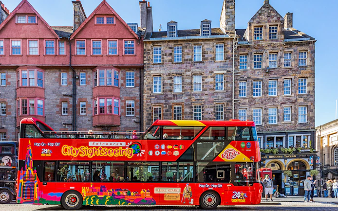 Hop-On Hop-Off bus in front of historic Edinburgh buildings.