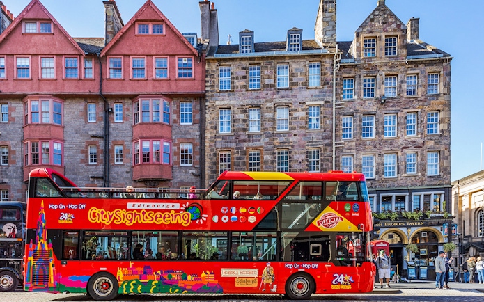 Hop-On Hop-Off bus in front of historic Edinburgh buildings.