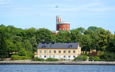 Burg auf Kastellholmen in Stockholm with Swedish flag and surrounding greenery.