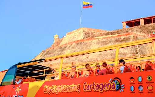 People on a City Sightseeing bus tour in Cartagena with Castillo San Felipe in the background.
