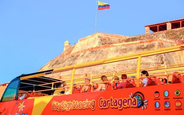 People on a City Sightseeing bus tour in Cartagena with Castillo San Felipe in the background.