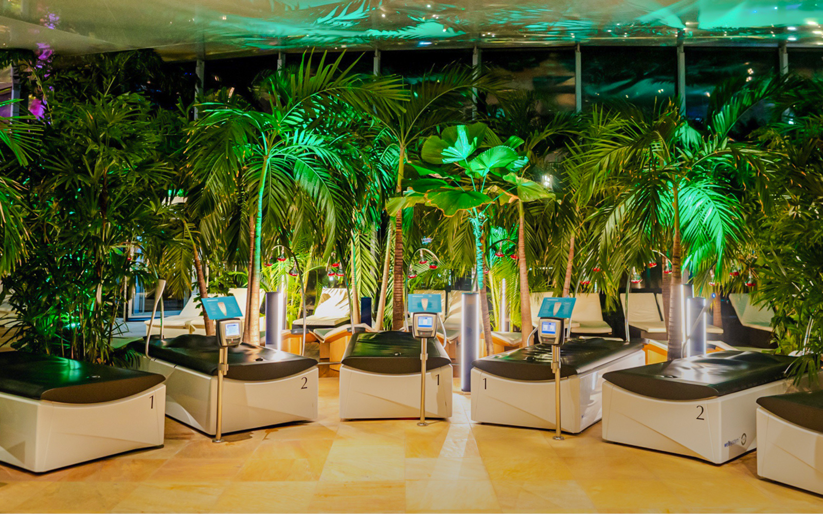 Hydromassage beds in the galaxy zone at Therme Bucharest at night surrounded by lush greenery.