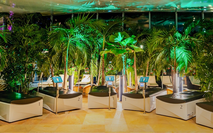 Hydromassage beds in the galaxy zone at Therme Bucharest at night surrounded by lush greenery.