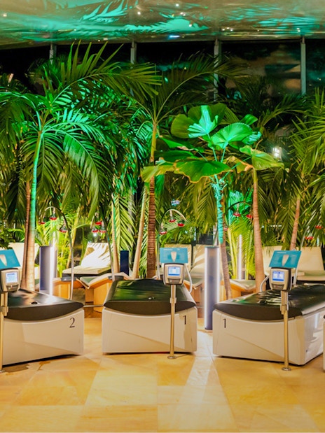 Hydromassage beds in the galaxy zone at Therme Bucharest at night surrounded by lush greenery.