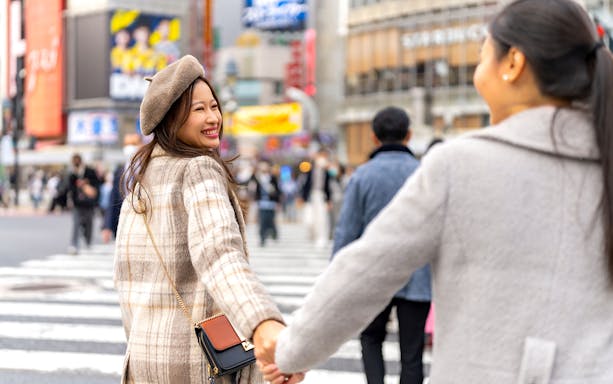 Couple holding hands at Shibuya Crossing, Tokyo, during a personalized photoshoot.