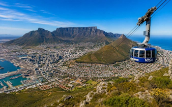 Cable car ascending Table Mountain with Cape Town cityscape below.