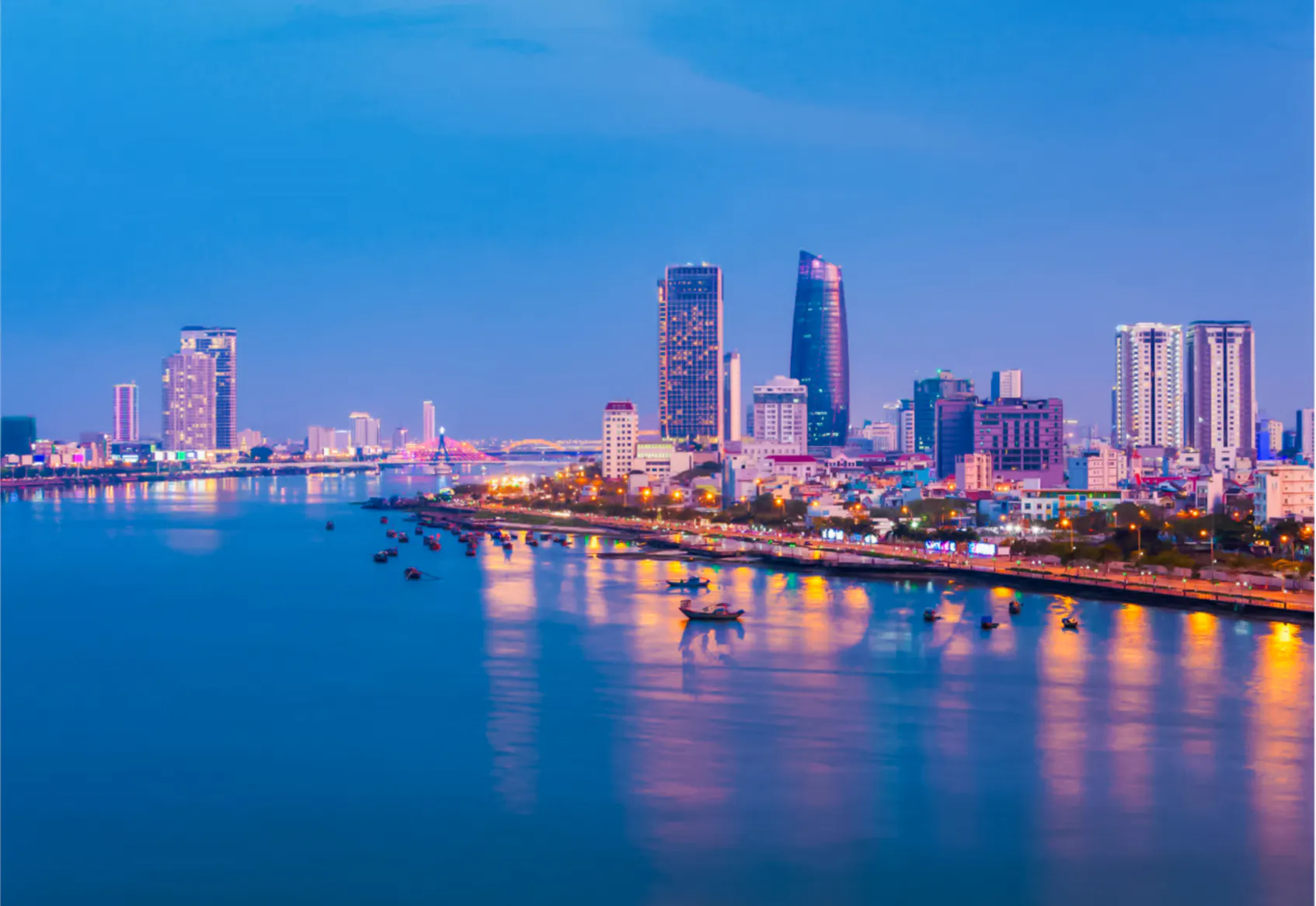 Da Nang skyline at night with illuminated buildings and river reflections.