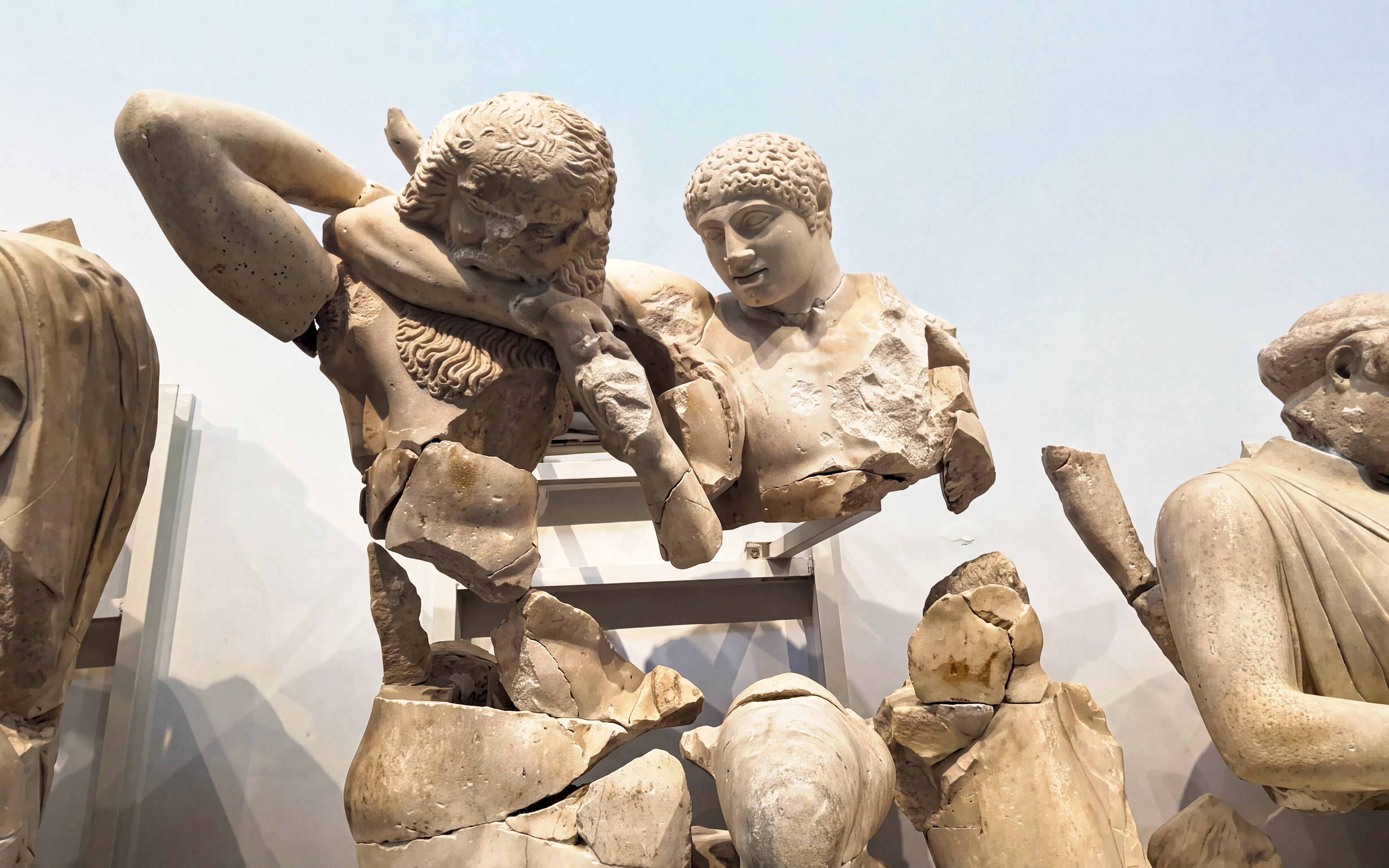 Ancient Greek statues in the Archaeological Museum of Olympia, depicting a mythological scene.