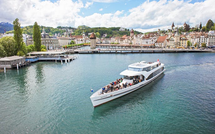 Panorama-yacht Saphir cruising on Lake Lucerne with cityscape in the background.