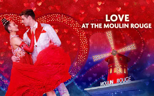 Dancers in red attire at Moulin Rouge with windmill backdrop, Valentine's Day theme.