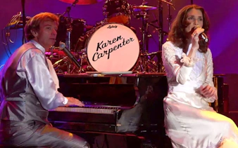 Performers on stage during Carpenters Legacy show, with a piano and drum set.