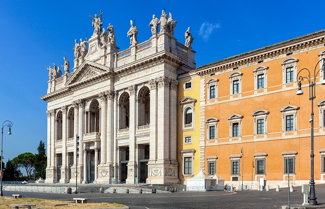 Facade of the Archbasilica of St John Lateran in Rome with statues and columns.
