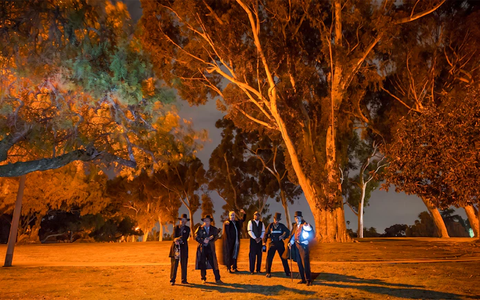Group in period costumes on San Diego Ghosts & Gravestones Tour at night.