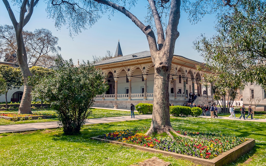 Third courtyard of Topkapi Palace with garden and visitors exploring the historic architecture.