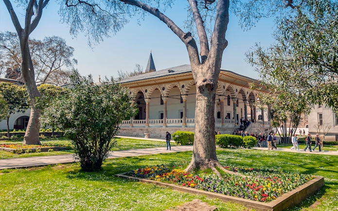 Third courtyard of Topkapi Palace with garden and visitors exploring the historic architecture.
