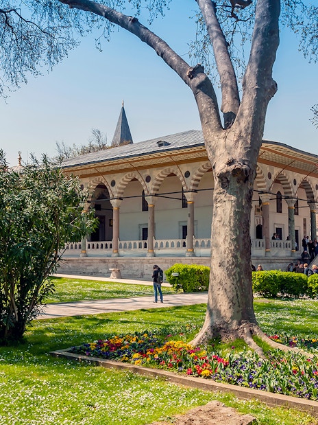 Third courtyard of Topkapi Palace with garden and visitors exploring the historic architecture.