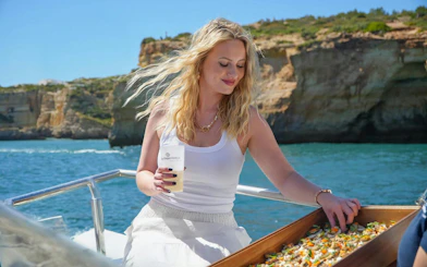Woman enjoying canapés on a boat near Benagil Caves, Algarve.