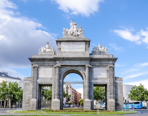 Puerta de Toledo in Madrid with a hop-on hop-off tour bus nearby.