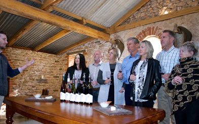 Group wine tasting in Barossa stone cellar with guide explaining.