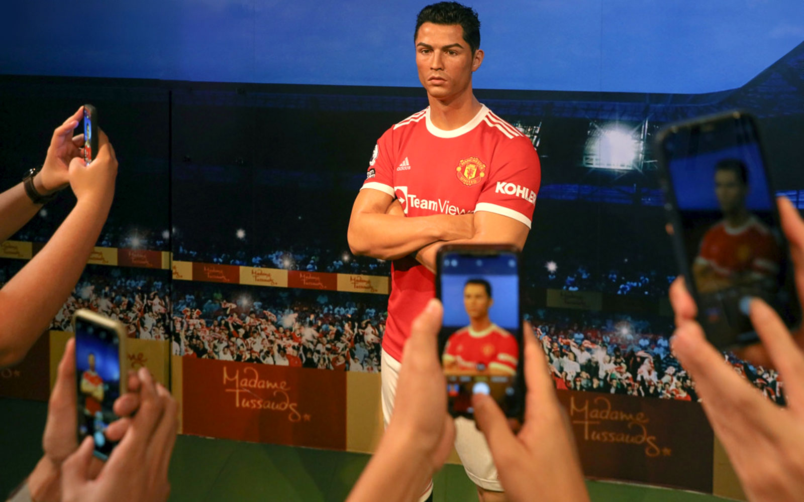 Wax figure of a football player at Madame Tussauds Hong Kong, surrounded by visitors taking photos.