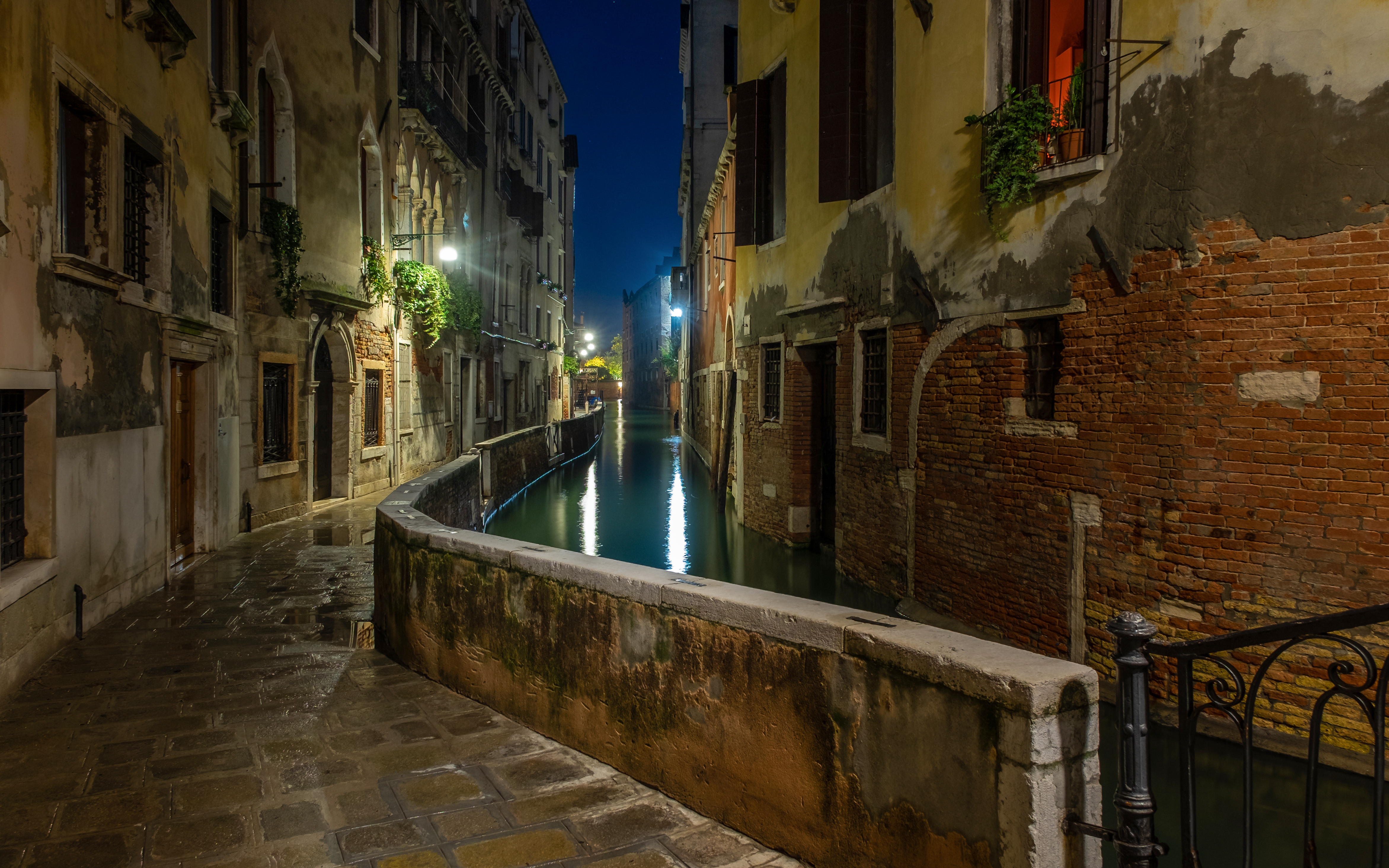 Venice canal at night with illuminated buildings and reflections on the water.