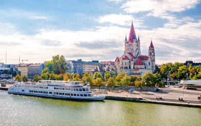 St Francis of Assisi Church viewed from Reichsbrücke bridge with a riverboat in Vienna.