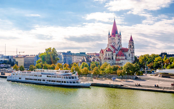 St Francis of Assisi Church viewed from Reichsbrücke bridge with a riverboat in Vienna.