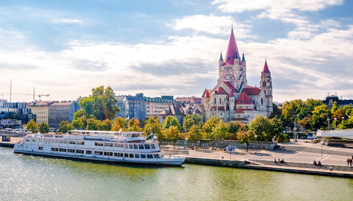 St Francis of Assisi Church viewed from Reichsbrücke bridge with river and boat in foreground.