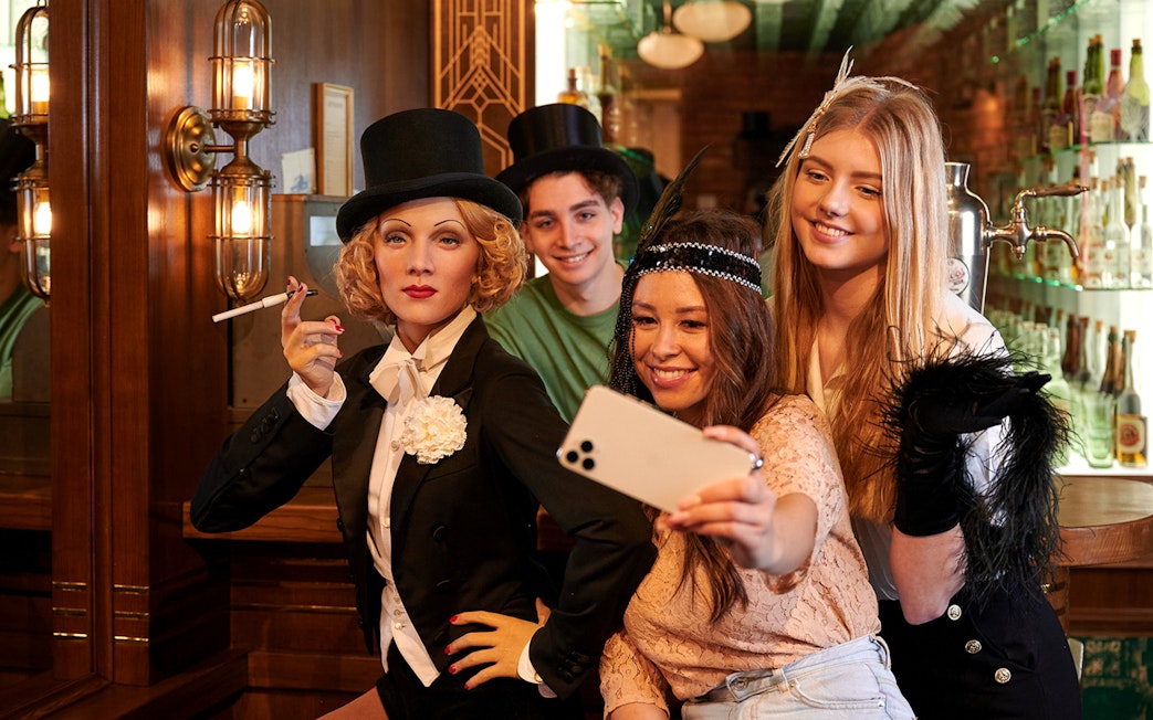 Visitors taking a selfie with Marlene Dietrich wax figure at Madame Tussauds Berlin.