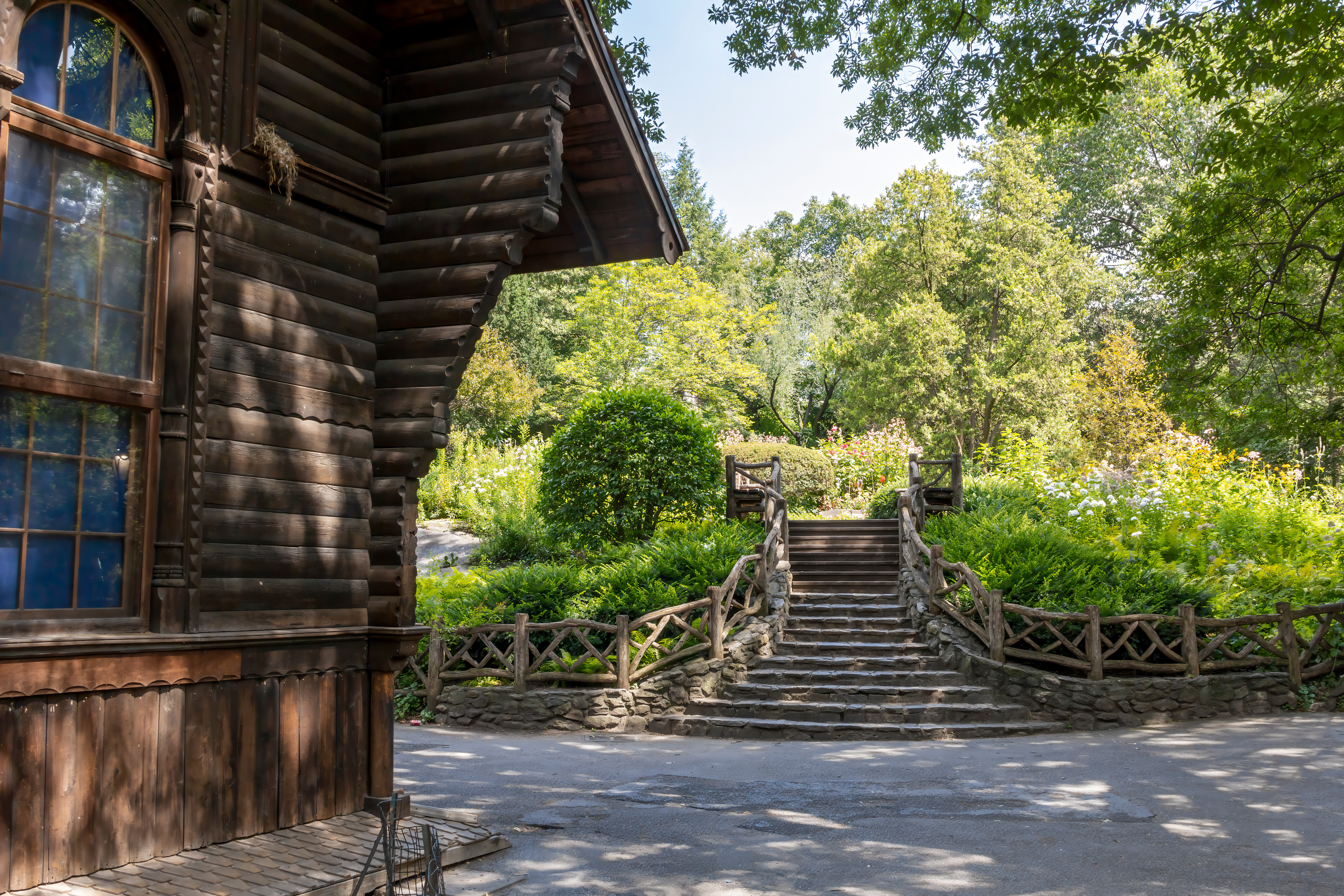 Stone steps leading to Shakespeare Garden surrounded by lush greenery and a rustic wooden building.