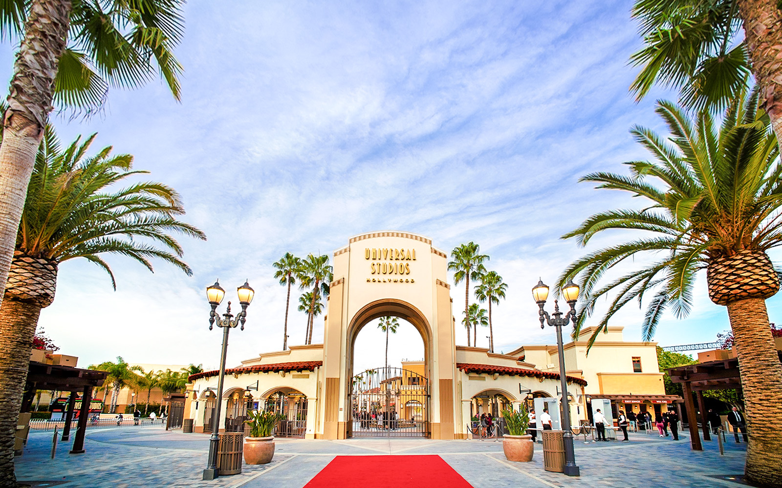 Entrance archway of Universal Studios Hollywood with palm trees and red carpet.