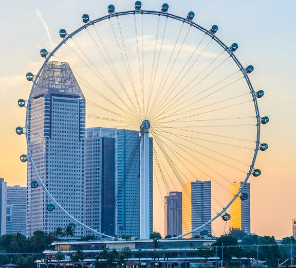 Singapore Flyer with city skyline at sunset, view from Marina Bay.