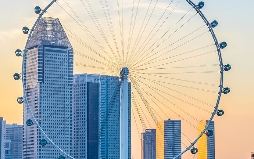 Singapore Flyer with city skyline at sunset, view from Marina Bay.