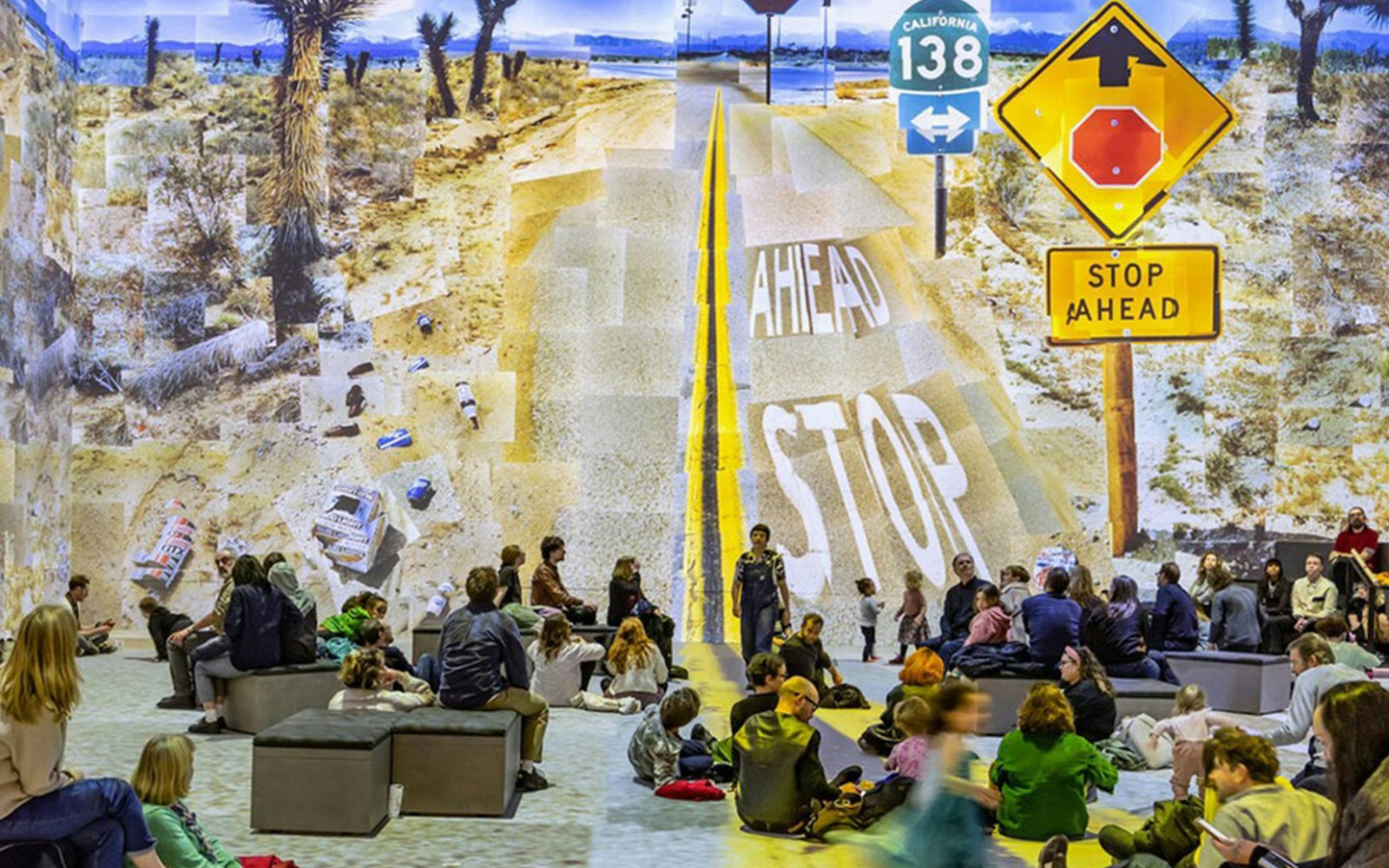 Visitors viewing David Hockney's "Bigger & Closer" exhibit with desert road collage.