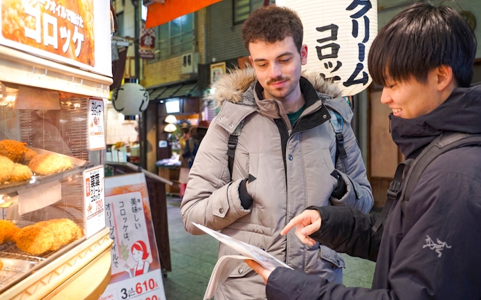 Tourists exploring food stalls at Nishiki Market, Kyoto, during a brunch tour.