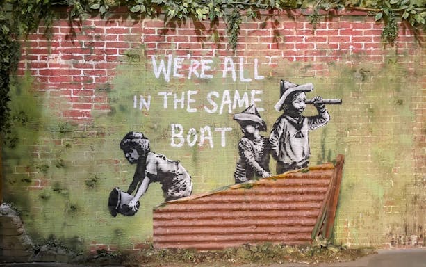 Street art of children with "We're all in the same boat" at Banksy Museum, Amsterdam.