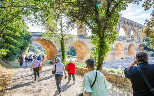 Visitors walking towards Pont du Gard aqueduct in France.