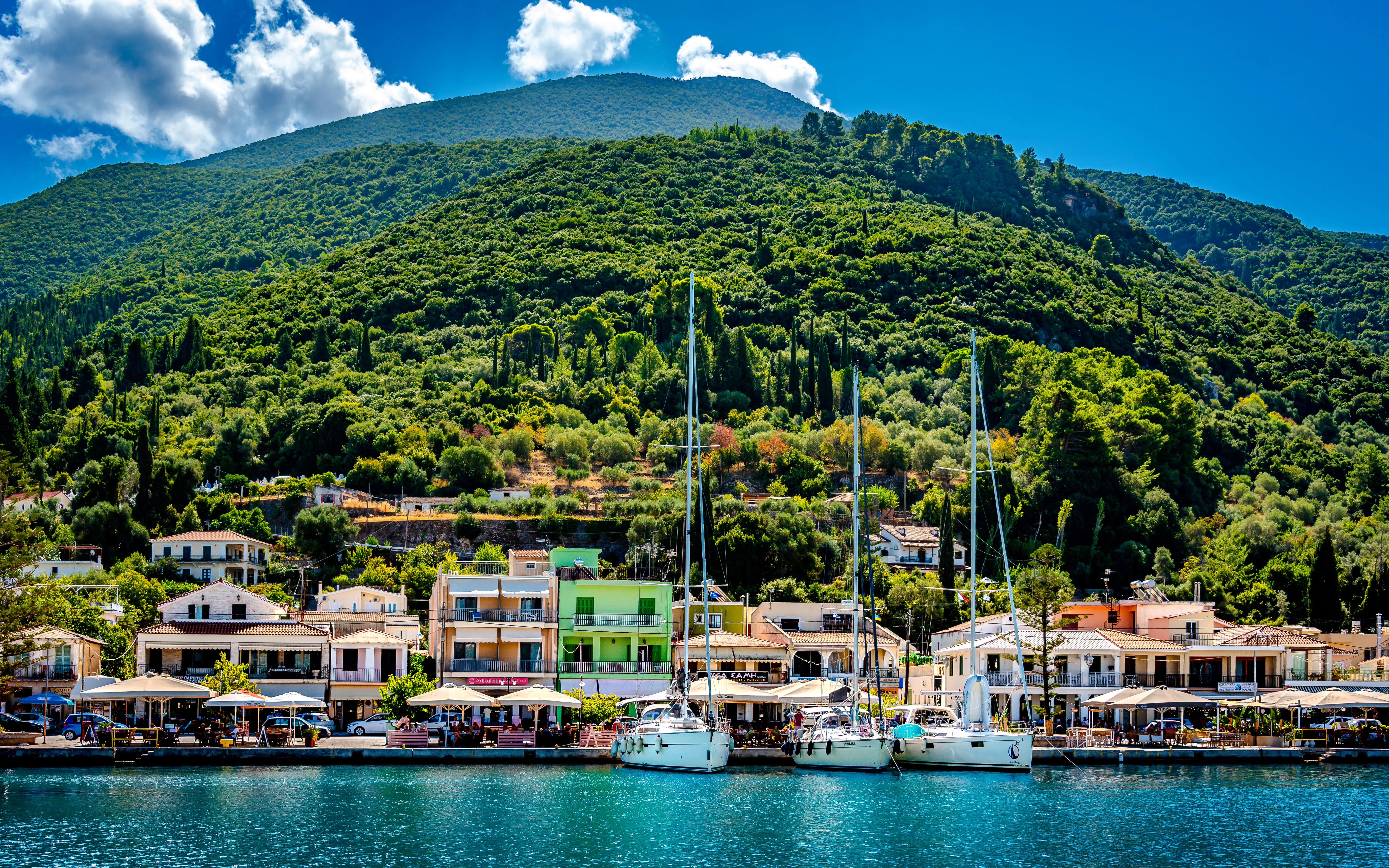 Sailboats docked at Sami Harbour with lush green hills in Kefalonia.