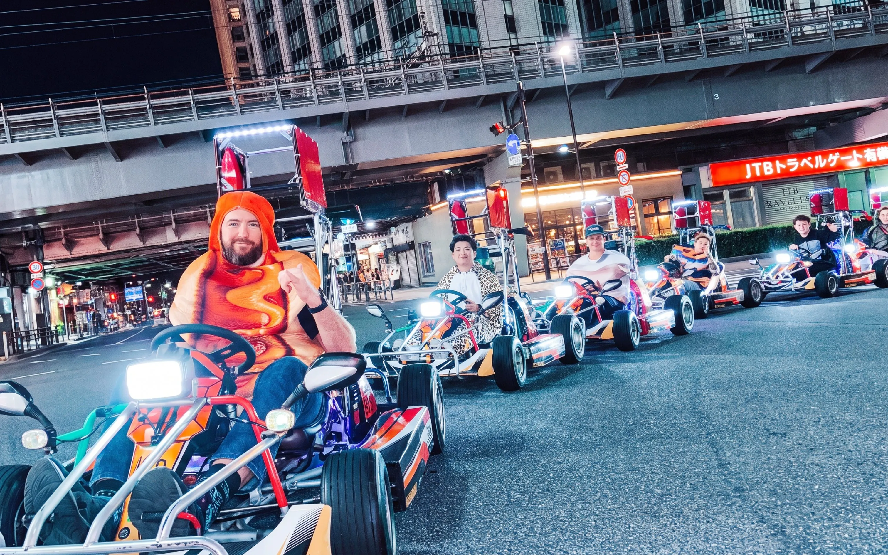 Go-kart riders in costume driving through Shibuya at night during NEO SHIBUYA EDGE experience.