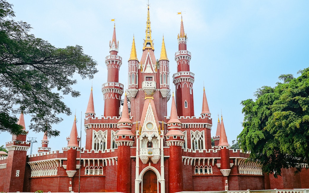 Red castle replica at Taman Mini Indonesia, Jakarta, surrounded by trees.