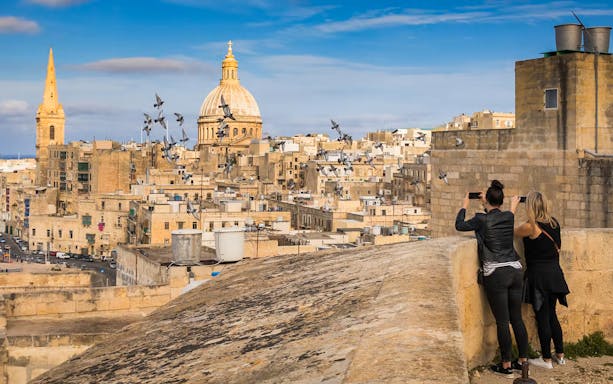 Valletta skyline with St. Paul's Cathedral dome, tourists taking photos, Malta.