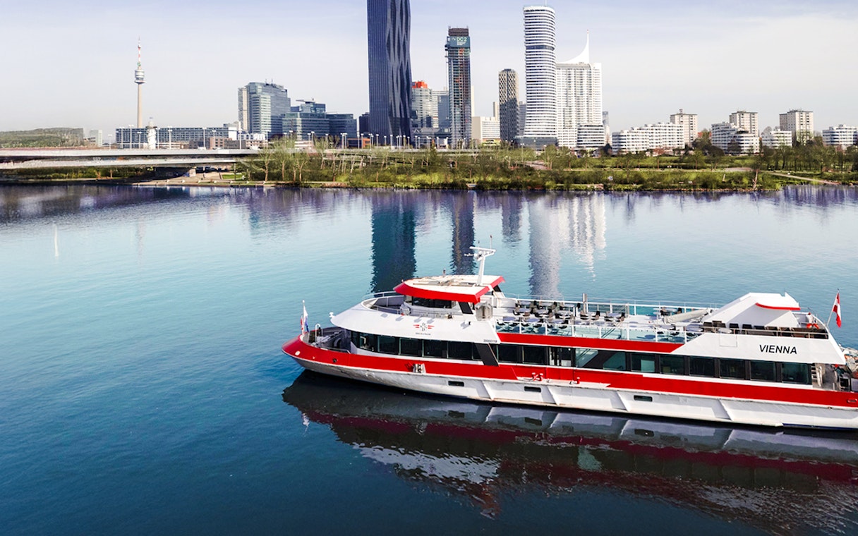 Aerial view of MS Vienna boat cruising on the Danube River with Vienna skyline, Austria.