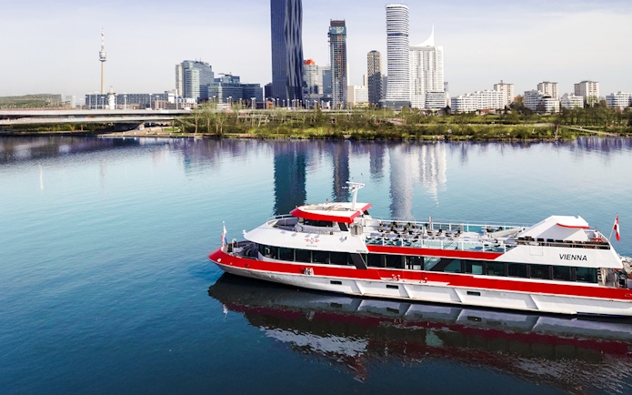 Aerial view of MS Vienna boat cruising on the Danube River with Vienna skyline, Austria.